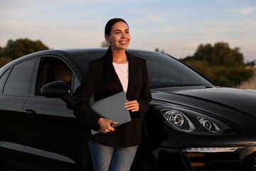 Wall Mural - Happy young woman with laptop near car outdoors