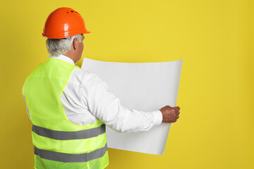 Wall Mural - Engineer in hard hat with draft on yellow background, space for text