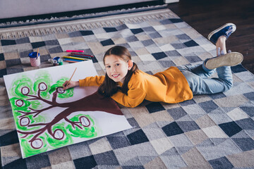 Sticker - Full size photo of cute small girl lying floor draw family tree dressed orange outfit cozy day light home interior living room