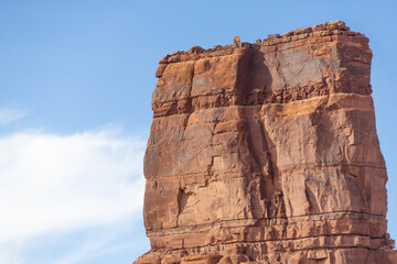 The side of a towering red rock formation with blue sky and copy space.