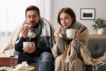 Canvas Print - Cold symptom. Couple with cups of drink suffering from fever on sofa at home