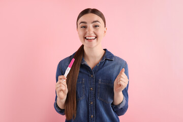 Sticker - Happy woman holding pregnancy test on pink background