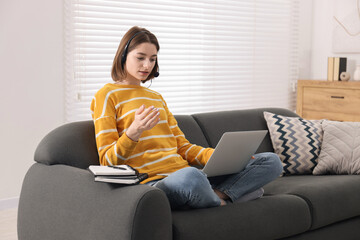 Wall Mural - Teenager in headset having video chat via laptop at home. Remote work