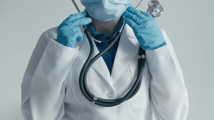 Poster - In a clinical setting, a healthcare provider in protective gear and a stethoscope is prepared for consultation and treatment, emphasizing safety through the use of gloves and masks