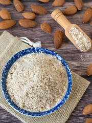 Wall Mural - Homemade almond flour made with raw nuts on wooden table. Top view. Healthy gluten-free alternative for baking and cooking.