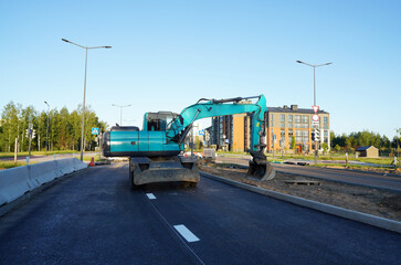 Excavator on road construction. Screeding ground for installing borders, curbs concrete blocks at road. Roadworks, construction site. Bucket wheel excavator on road construction at construction site.