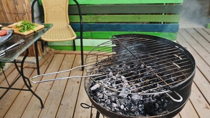 Outdoor barbecue setup with empty grill and fresh ingredients on a patio ready for a summer cookout or family gathering