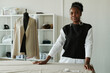 © pressmaster - Young confident African American seamstress in casual apparel and stylish accessories looking at camera while standing by workplace
