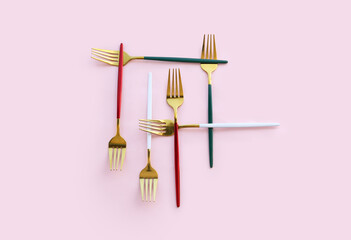 Wall Mural - Golden forks on pink background