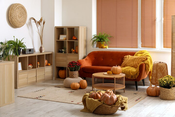 Poster - Interior of cozy living room with brown sofa, wooden furniture and pumpkins