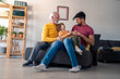 © Dorde - A cheerful trio, including a senior man, his adult son, and young grandson, shares a playful moment on a comfortable sofa, surrounded by a cozy home setting.