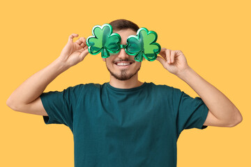 Wall Mural - Happy young man with party glasses on yellow background. St. Patrick's Day celebration