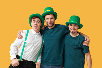 Wall Mural - Happy young men in leprechaun's hats hugging on yellow background. St. Patrick's Day celebration