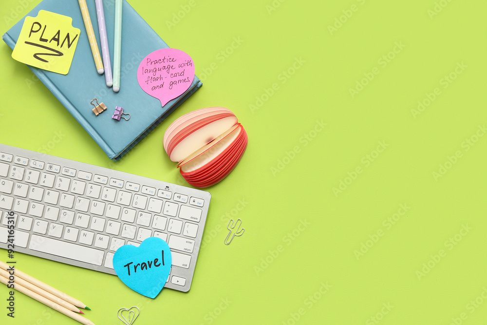 Sticky notes with to do plans, notebook and computer keyboard on green background. New year goals concept