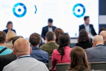 business professionals attending a conference presentation with speakers discussing information and 