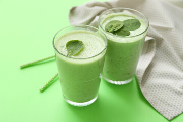 Wall Mural - Glasses of fresh spinach smoothie on green background