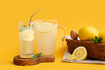 Wall Mural - Glass and jug of fresh lemonade with mint on yellow background