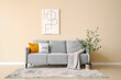 © Pixel-Shot - Soft sofa with plaid and cushion, picture on wall and decorative olive tree in interior of living room