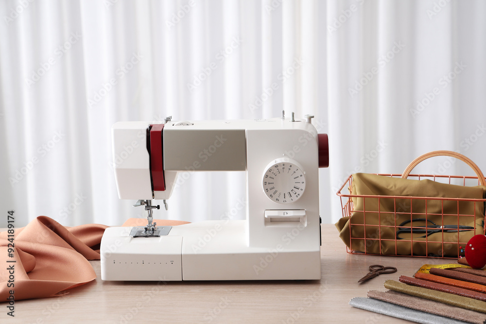 Modern sewing machine with fabric and tailor's supplies on wooden table