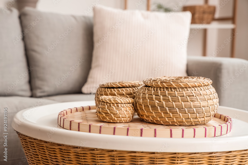 Cozy sofa with cushion and wicker coffee table with boxes in living room, closeup
