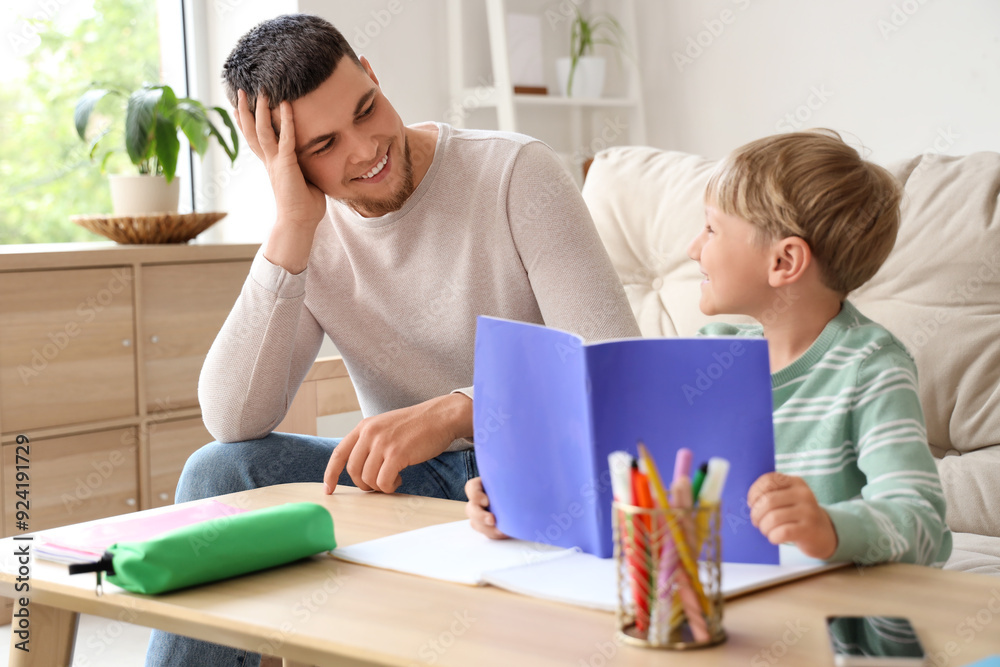 Father and his little son doing homework together at home