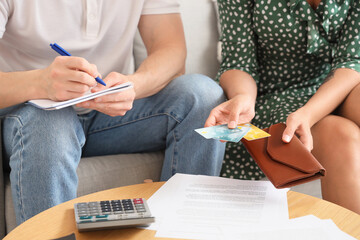 Sticker - Young woman holding credit cards while her husband writing down something at home, closeup. Bankruptcy concept