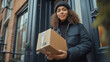 © Ramses - female delivery person  holding parcel standing near the door