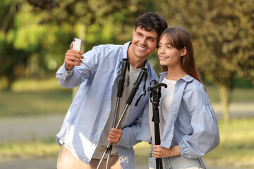 Poster - Young couple training with walking poles taking selfie outdoors