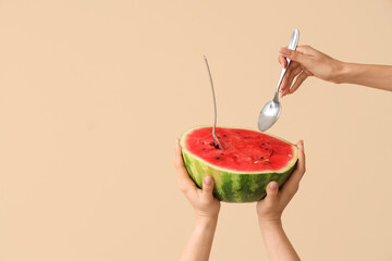 Poster - Female hands with half of sweet watermelon and spoons on beige background