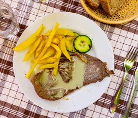 Wall Mural - Appetizing grilled beef steak with roquefort sauce served on platter with french fries and zucchini