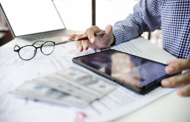 Wall Mural - Asian businessman working in office using tablet for online business with business documents. analyzing marketing plan to start new business