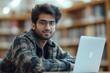 © Just Bella - Young Indian male student wearing headset talking to camera sitting in library, Generative AI