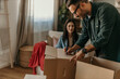 © La Famiglia - Couple smiling and having fun during a packing clothes into a boxes at home