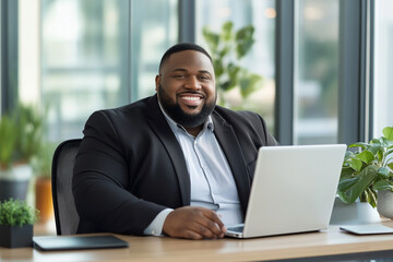 Poster - Plus size man with a big smile on his face is sitting at a desk with a laptop 