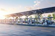 © Anna - Electric Vehicle Charging Station at Modern Transportation Hub with Solar Panels and Cars at Sunset
