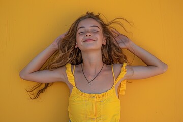 Wall Mural - A girl in a yellow shirt is laying on her back with her arms spread out