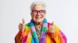 © indyntk - Elderly person in vibrant LGBTQ+ fashion smiling and giving thumbs up against isolated white background joyful confident expression
