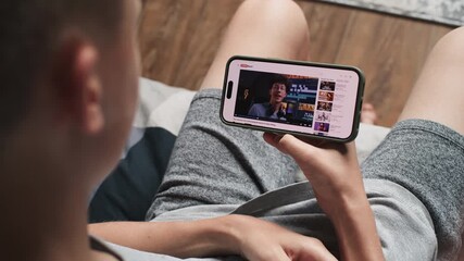Poster - close up of caucasian teenage boy watching blog about video editing on mobile phone while sitting on