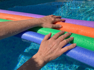 Wall Mural - Woman and rainbow coloured foam float in swimming pool