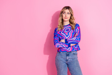 Wall Mural - Photo of blonde young girl folded arms wearing trendy bright sweatshirt looking empty space brainstorming isolated on pink color background