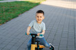 © Andrii Yalanskyi - A cute happy caucasian toddler boy of three or four years old rides a bicycle or balance bike in the park. Summer activity for children.