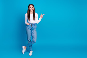 Wall Mural - Full length photo of lovely teen lady posing model point empty space dressed stylish white garment isolated on blue color background