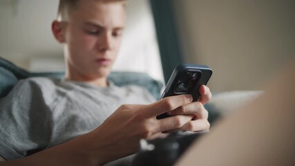 Poster - caucasian teenager chats in messaging app with friends or watches content using mobile phone while s