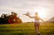 © Yura Yarema - Playful preteen girl run with airplane on background amazing summer sunset and beautiful mountains. Dream freedom concept. Child runs on field holding in hands toy aircraft