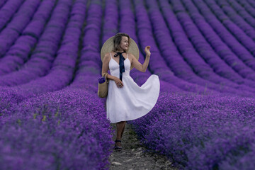 Canvas Print - A woman is standing in a field of purple flowers