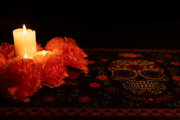 Three candles in soft glow, surrounded by colorful marigold flowers, set against a black background