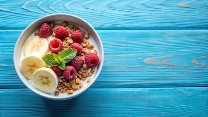 Wall Mural - Bowl of yogurt and granola with fresh raspberries and banana on blue background, yogurt, granola, raspberries, banana