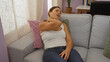 © Krakenimages.com - Woman suffering neck pain sitting on sofa in cozy home interior with natural light filtering through curtains