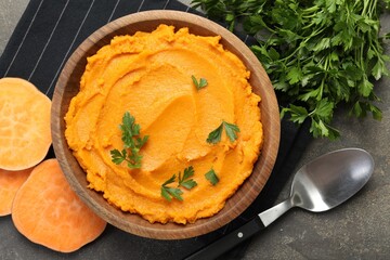 Delicious mashed sweet potatoes with parsley served on gray textured table, flat lay