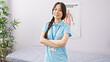 © Krakenimages.com - Confident young asian woman healthcare professional standing with her arms crossed in a hospital room.